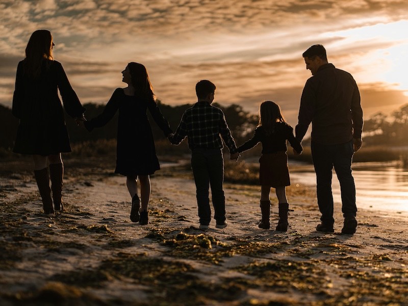 A family walking together along the shore at sunset